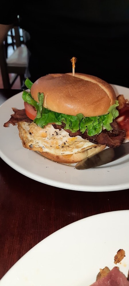 Bacon, lettuce and tomato on a bun topped with a fried egg
