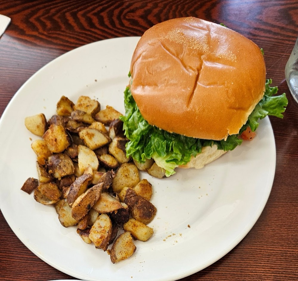 Burger on a toasted bun with crisp lettuce, served with a side of house panfries