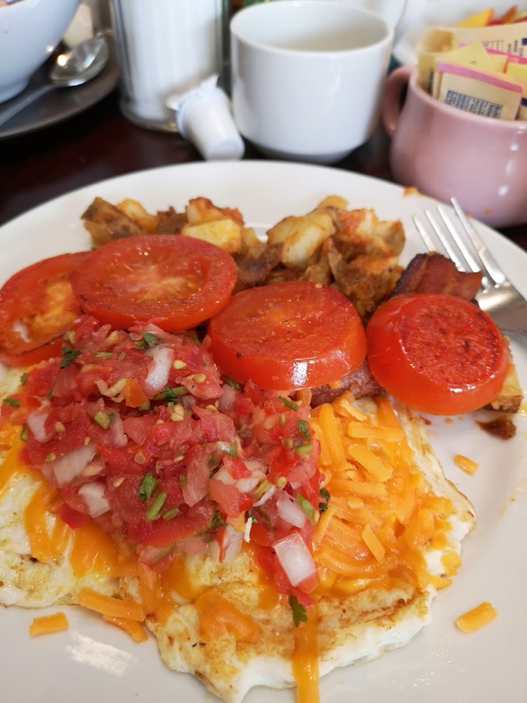 Eggs topped with fresh salsa and grated cheddar, with grilled tomato, bacon and panfries